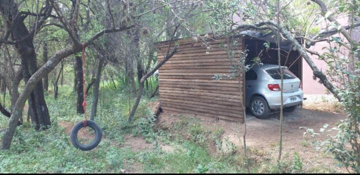 un coche aparcado frente a un cobertizo de madera en Cabaña Thaqu en Merlo