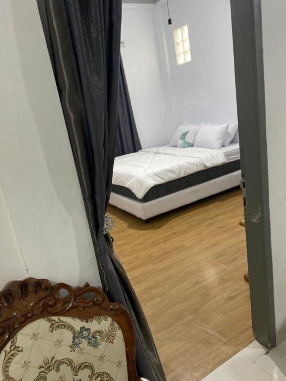 a room with a bed and a window with a bed frame at Lorent Hostel Near Padang Beach in Padang
