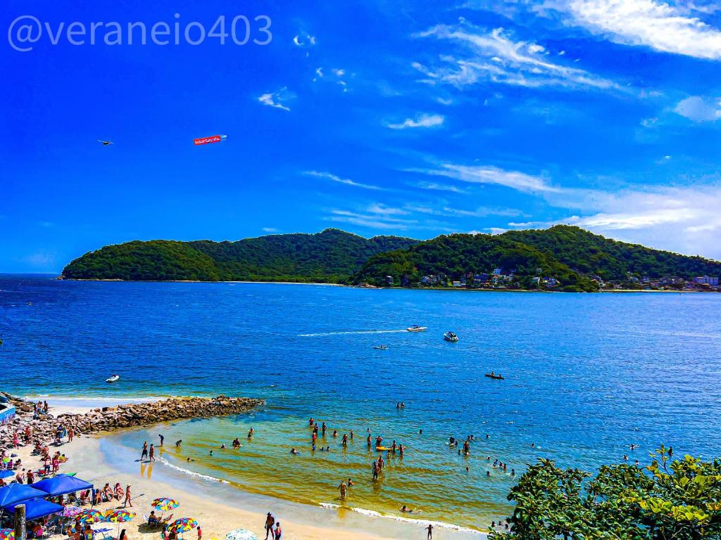 a group of people on a beach in the water at Apartamento frente mar c/ar P/ 6 hóspedes in São Vicente