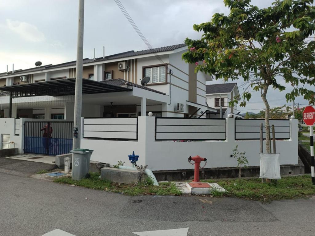 une maison dotée d'une clôture blanche et d'une bouche d'incendie rouge dans l'établissement IN HOMESTAY CORNER BATU PAHAT, à Batu Pahat