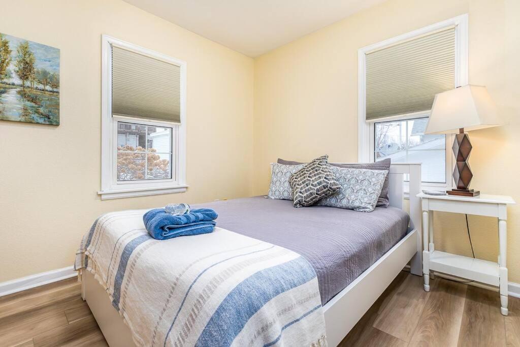 a small bedroom with a bed and two windows at Oaklie's Bungalow - Charming Home in Dubuque in Dubuque