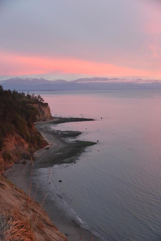 a view of the ocean at sunset at Cliffside Cottage in Oak Harbor