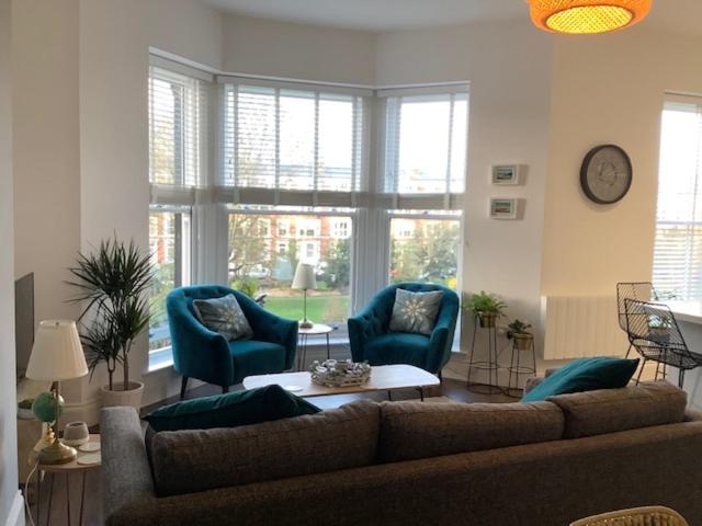 a living room with a couch and two blue chairs at Brooklands Hideaway in Scarborough