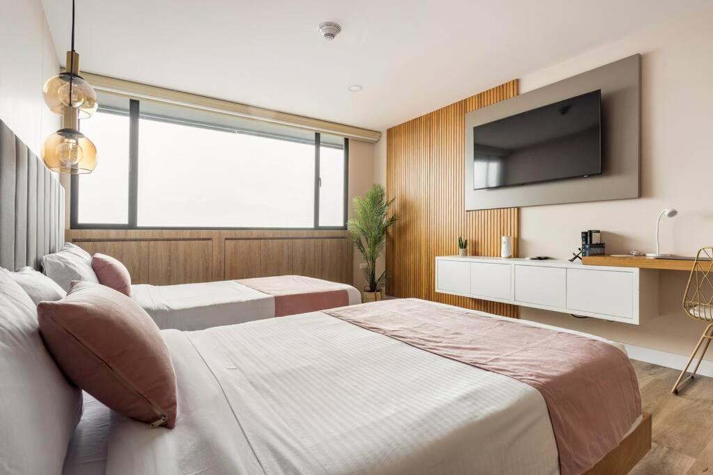 1 dormitorio con 2 camas y TV de pantalla plana en Suite - Go living & Suites, en Medellín