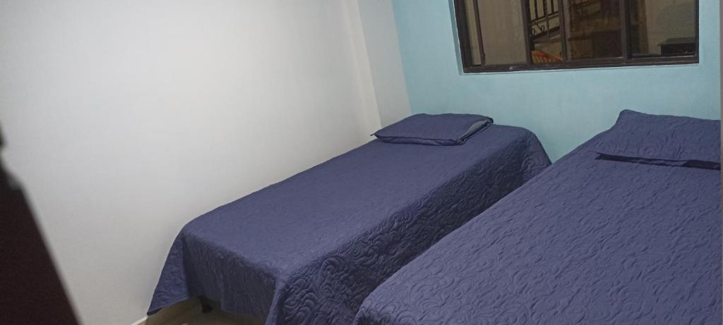 duas camas num quarto com lençóis roxos em Apartamento San Jose em Floridablanca