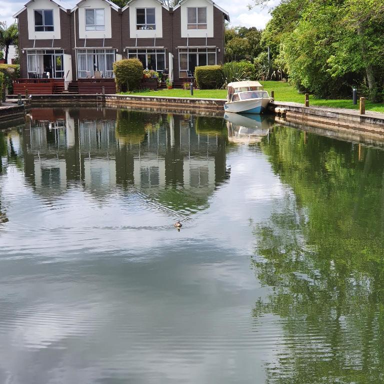 a boat docked in the water in front of a house at Kuirau Chalet Villa 3-bedroom Twin Lake in Rotorua