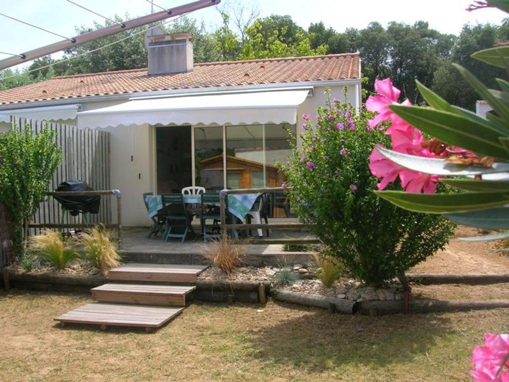 Cette maison dispose d'une terrasse avec une table et des fleurs. dans l'établissement Maison proche forêt, plage et commerces - 2 ch, terrasse, jardin clos, parking privé, animaux acceptés - FR-1-22-231, à La Tranche-sur-Mer