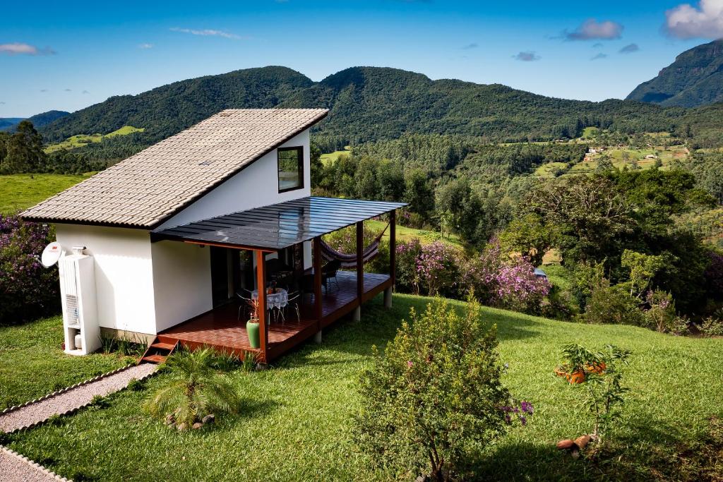 une petite maison sur une colline avec des montagnes en arrière-plan dans l'établissement Chalé Casal - Sítio Vale Encantado, à Treviso