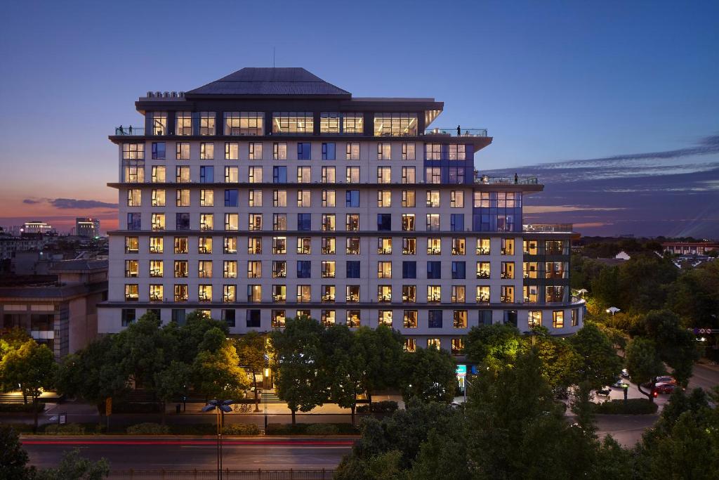 een groot gebouw met veel ramen die 's nachts verlicht zijn bij SSAW Boutique Hotel Yangzhou in Yangzhou