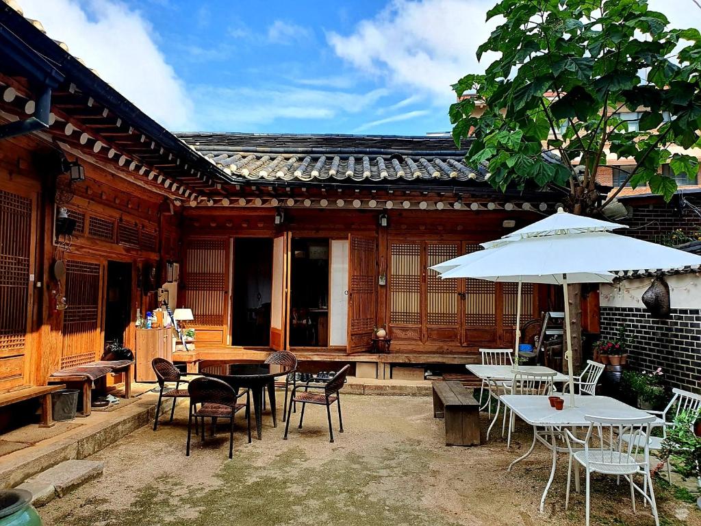 a patio with tables and chairs and an umbrella at NamHyunDang - Hanok Korean Traditional House in Seoul