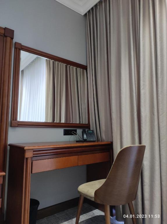 a mirror and a desk and a chair in a room at Mir Luxe Plaza in Tashkent