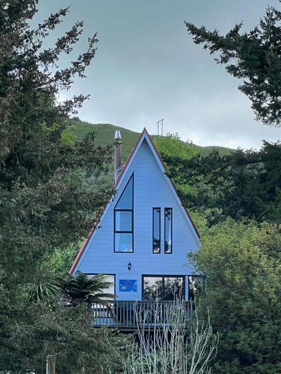 a blue house on top of a hill with trees at Pointy Bird, Tranquility, rejuvenating,pets welcome in Hamurana