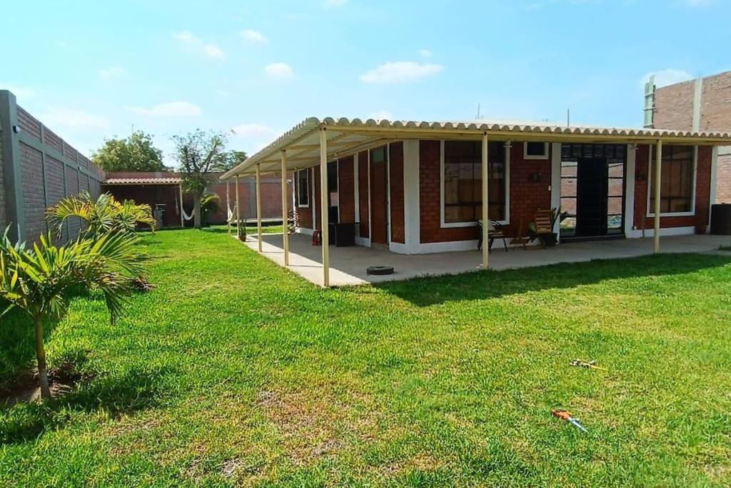 a house with awning in a yard with a grass field at La casa de Alex in Piura