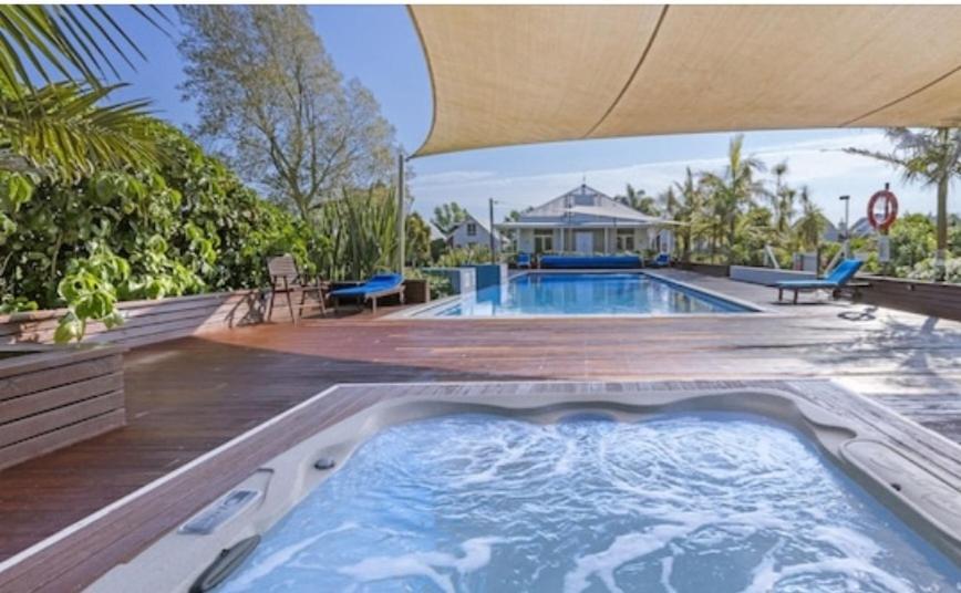 a swimming pool with a deck and a house at Kuituna on the Canal Villa, 3 bedrooms in Rotorua