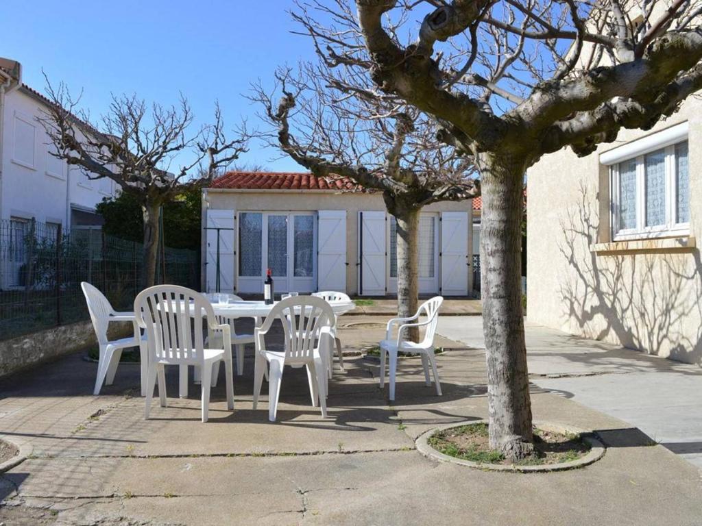 une table avec des chaises blanches et un arbre dans l'établissement Villa 5 pièces avec annexe, proche plage et commerces, terrasse et parking, SAINT PIERRE LA MER - FR-1-229D-209, à Saint Pierre La Mer