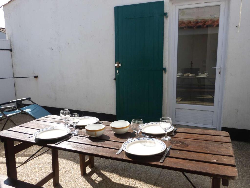 une table en bois avec des assiettes et des verres à vin dessus dans l'établissement Charmante maison avec mezzanine, piscine chauffée, proche de la mer à Brétignolles-sur-Mer - FR-1-224A-388, à Bretignolles-sur-Mer