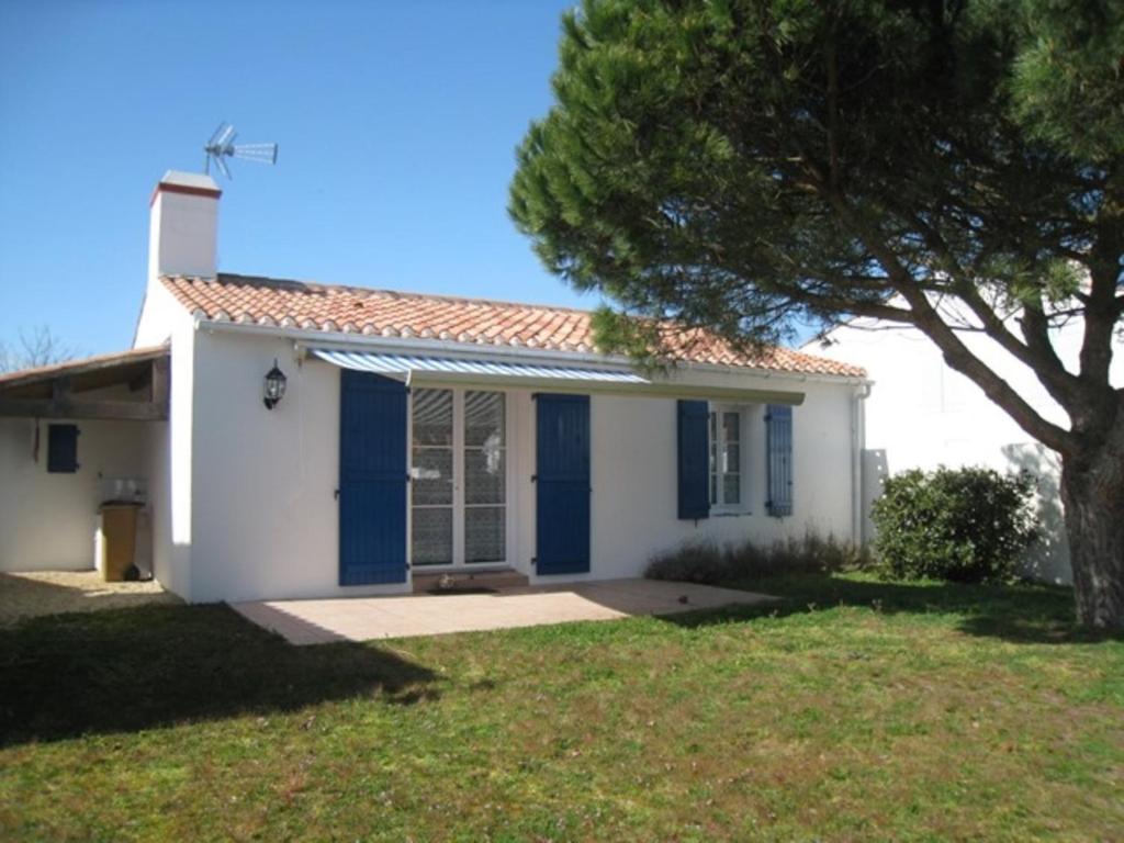 uma pequena casa branca com portas azuis e uma árvore em Maison L'Épine, 3 pièces, 5 personnes - FR-1-224B-515 em LʼÉpine