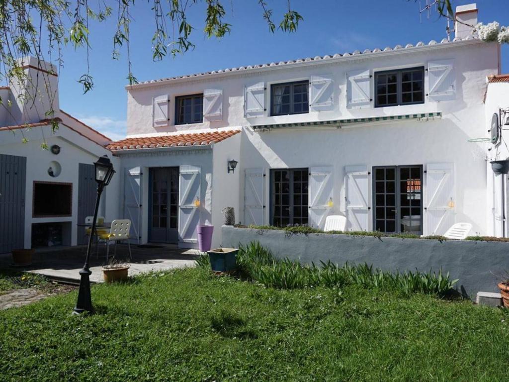 une maison blanche avec une pelouse devant dans l'établissement Maison confortable proche commerces, plage et port – 6 couchages, jardin clos avec terrasse et BBQ - FR-1-224B-453, à Noirmoutier-en-l'lle