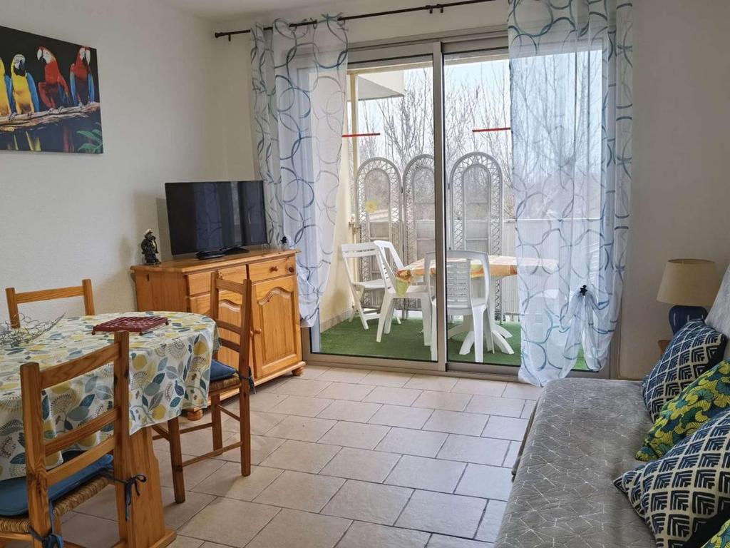 un salon avec une télévision et une table dans l'établissement Charmant appartement T2 cabine, proche plage, commerces, parking privé, terrasse sud-est, 5 pers - FR-1-326-582, à Marseillan