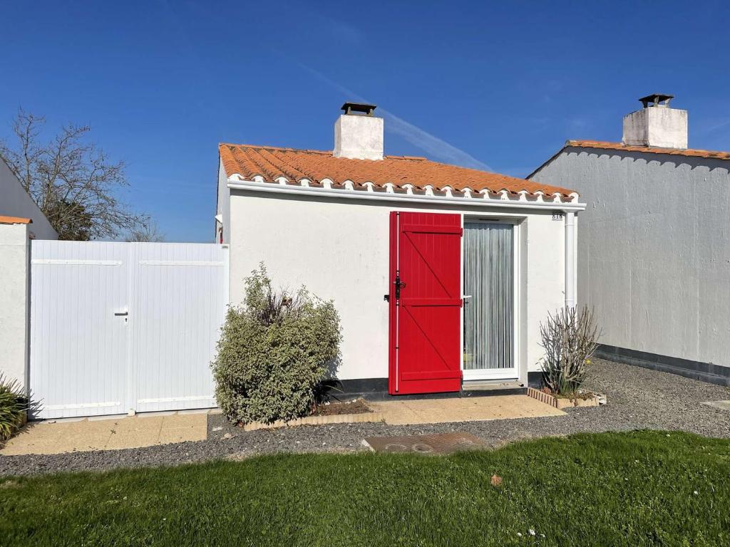 uma garagem vermelha com uma cerca branca e uma porta vermelha em Maison Bretignolles-sur-Mer, 2 pièces, 4 personnes - FR-1-224A-12 em Bretignolles-sur-Mer