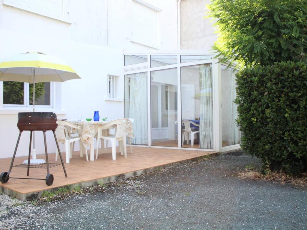 un patio avec une table, des chaises et un parasol dans l'établissement Maison près du port de La Cotinière, 4 couchages, terrasse, véranda, parking sur propriété - FR-1-246A-31, à La Cotinière