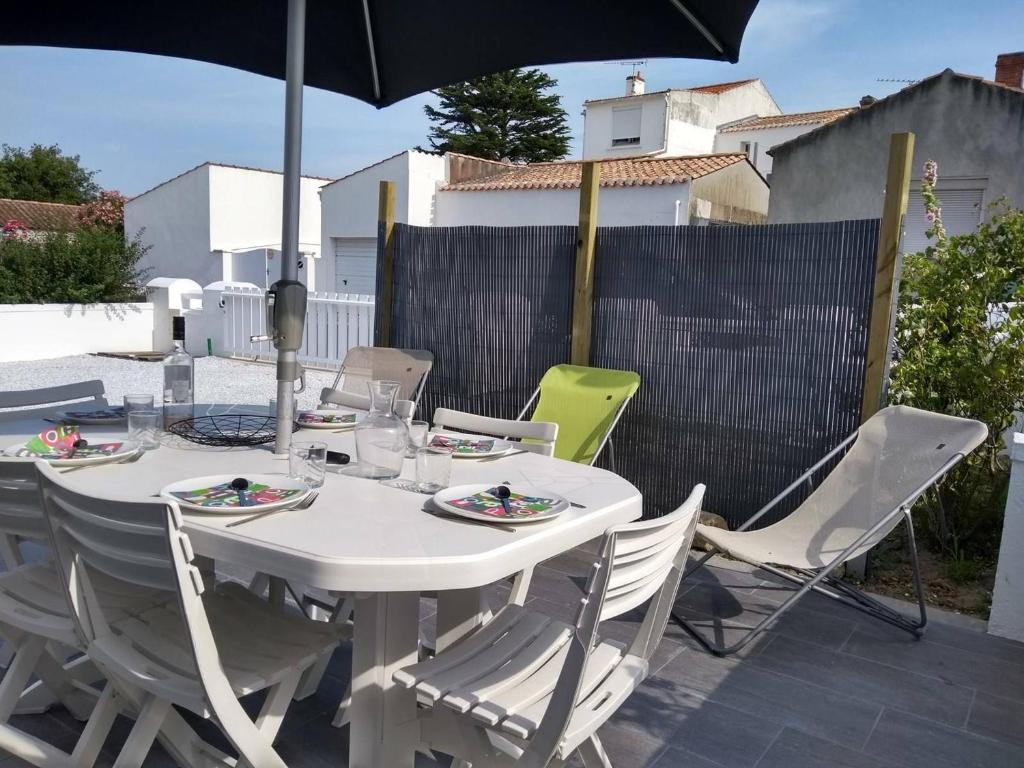 une table blanche avec des chaises et un parasol dans l'établissement Maison rénovée près de la plage avec jardin clos, 300m de la mer, La Guérinière - FR-1-224B-69, à La Guérinière