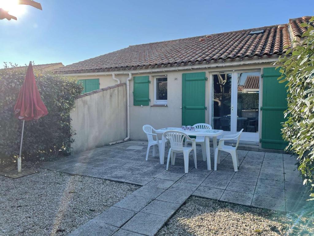 un patio avec une table, des chaises et un parasol dans l'établissement Maison à 200m de la mer, piscine chauffée, 4 couchages, parking privé, terrasse - Bretignolles-sur-Mer - FR-1-224A-50, à Bretignolles-sur-Mer