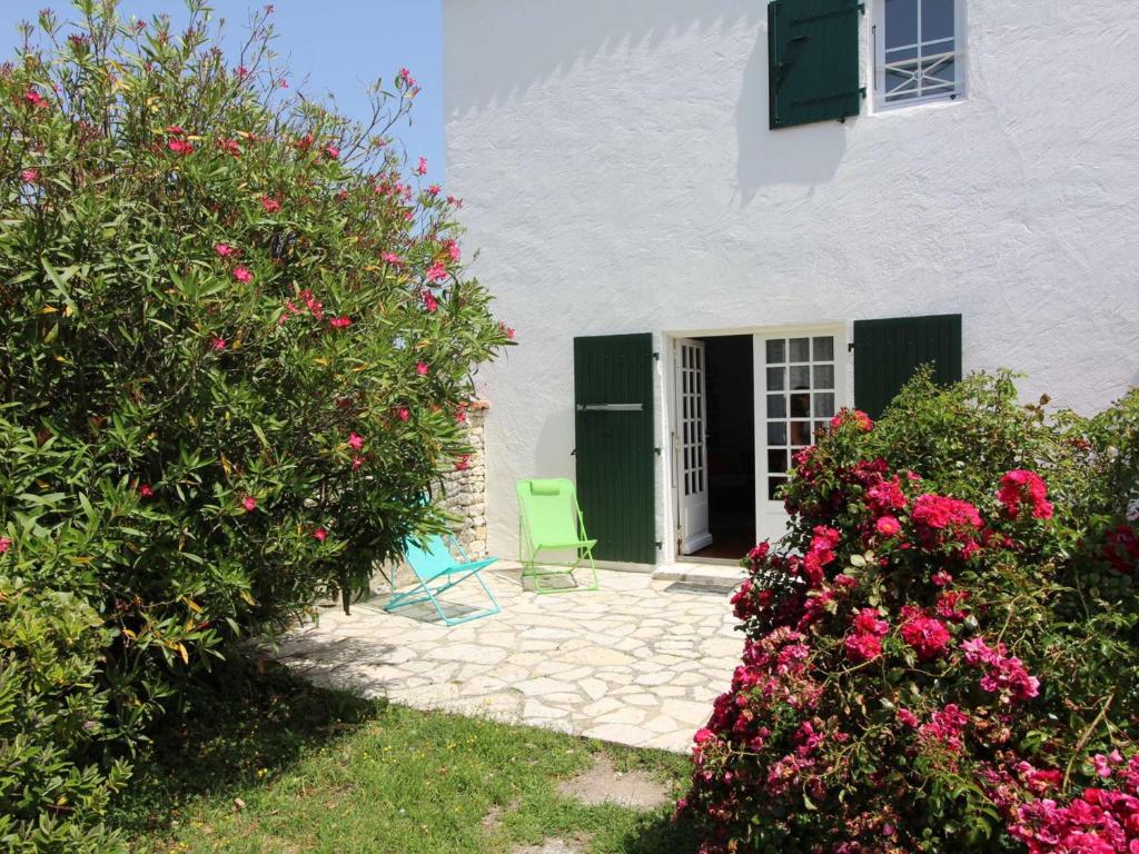 une maison blanche avec une porte verte et des fleurs dans l'établissement Maison Dolus-d'Oléron, 4 pièces, 7 personnes - FR-1-246A-119, à Dolus-d'Oléron