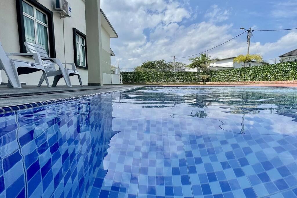 una piscina de azulejos azules con una silla junto a una casa en LAMAN KASEH Homestay Bukit Katil Melaka, en Ayer Keroh