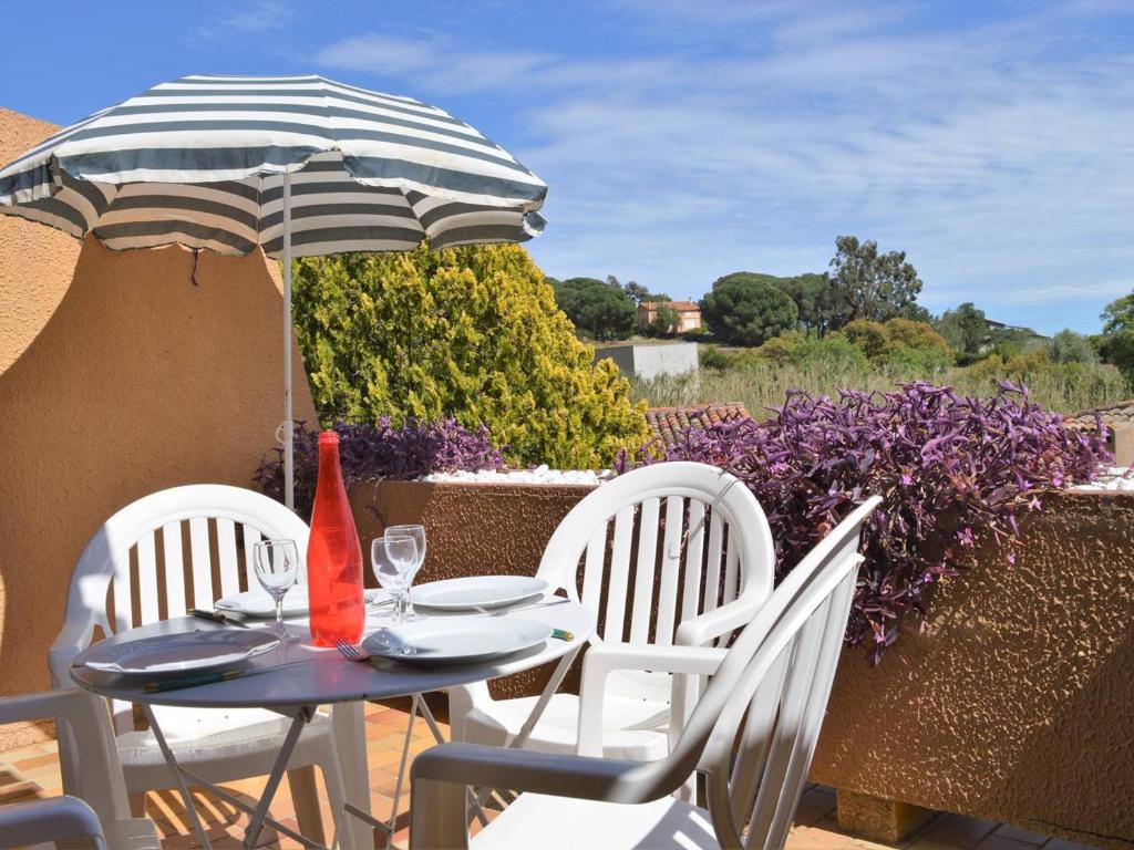 une table et des chaises avec un parasol sur une terrasse dans l'établissement Studio 4 couchages avec terrasse, parking et proche plage au Lavandou - FR-1-251-240, au Lavandou