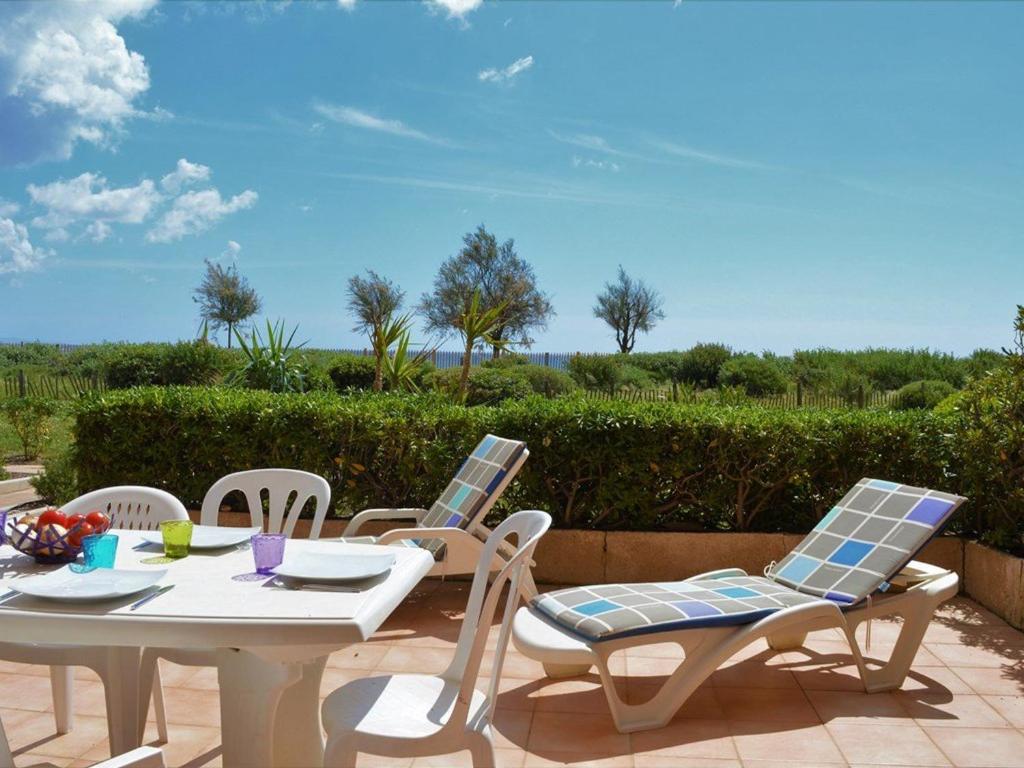 une table blanche et des chaises sur une terrasse dans l'établissement Appartement rénové en front de mer, 3 pièces, terrasse, parking, tout équipé, idéal familles, 6 pers. - FR-1-251-281, au Lavandou