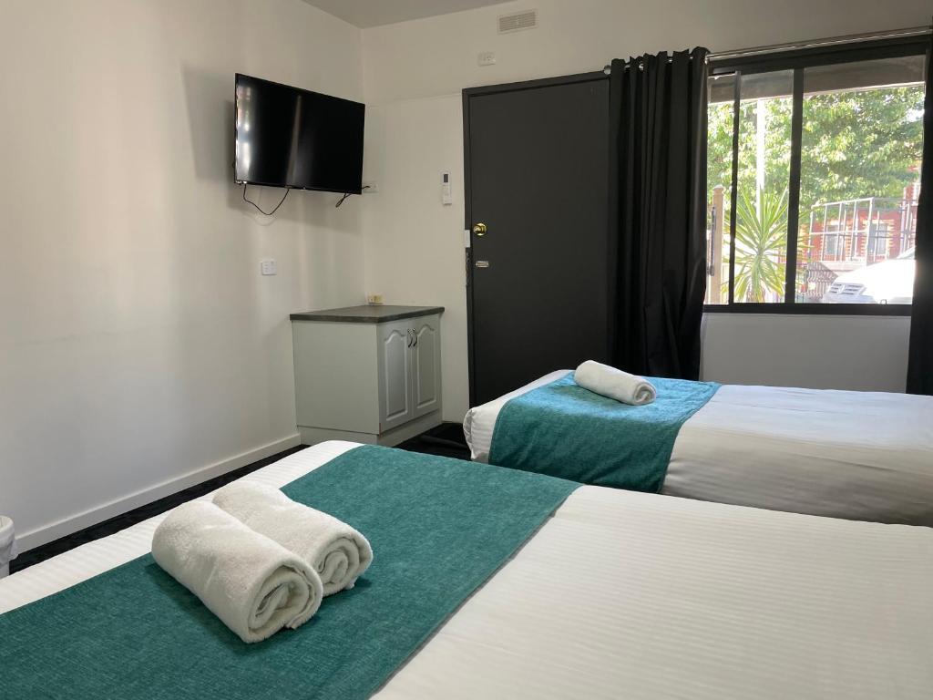 ein Hotelzimmer mit 2 Betten und Handtüchern darauf in der Unterkunft SHEPPARTON MOTOR INN Tudor House Motel in Shepparton