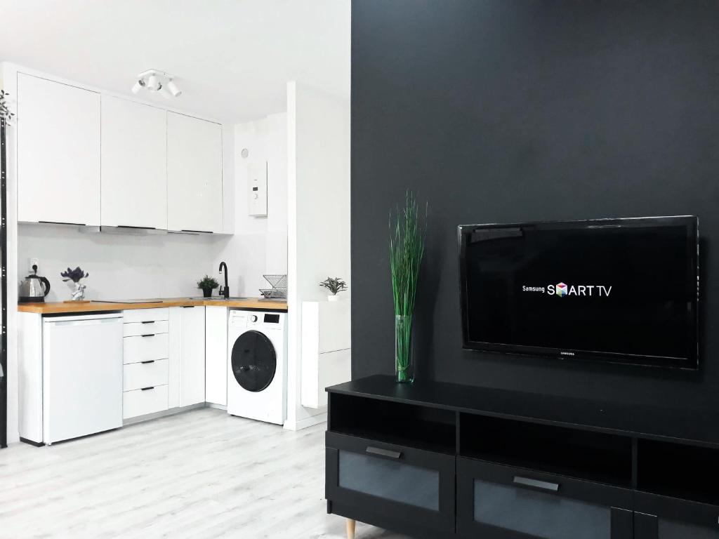 a kitchen with white cabinets and a tv on a black wall at Wera in Kłodzko