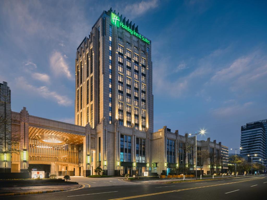 ein hohes Gebäude mit einem grünen Schild darüber in der Unterkunft Holiday Inn & Suites Kunshan Huaqiao, an IHG Hotel - F1 Racing Preferred Hotel in Kunshan