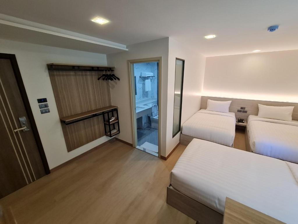 um quarto de hotel com duas camas e uma varanda em Thana Wisut Hotel - SHA Plus em Banguecoque