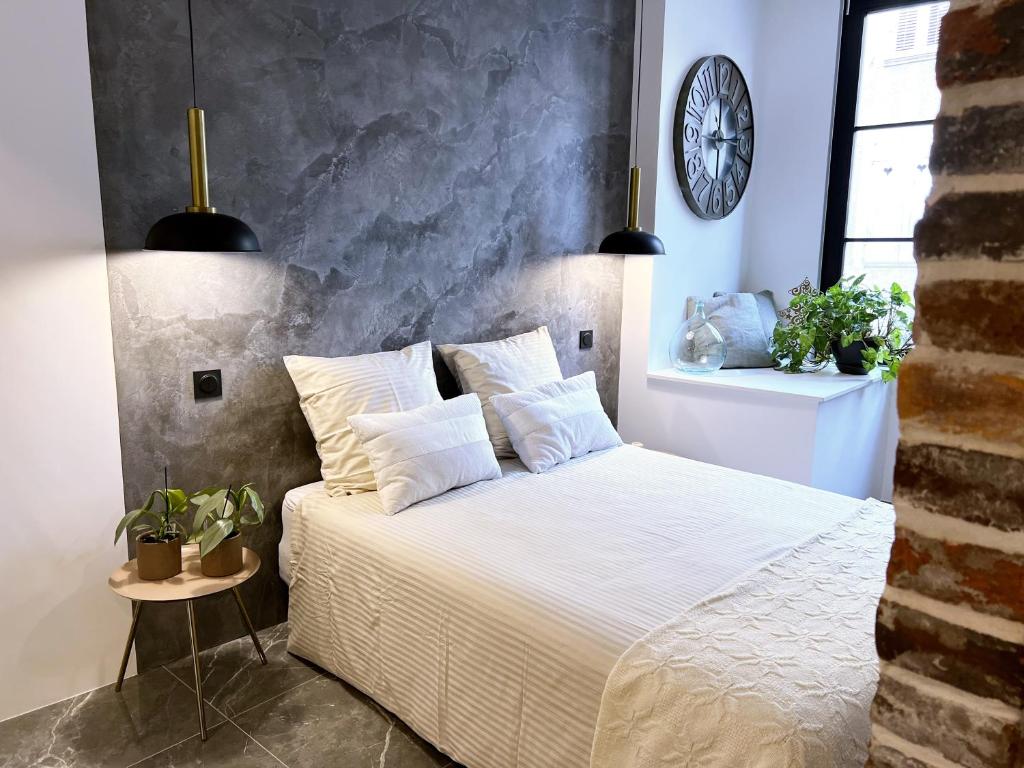 a bedroom with a white bed with a clock on the wall at Appartement - Centre Ville in Joigny