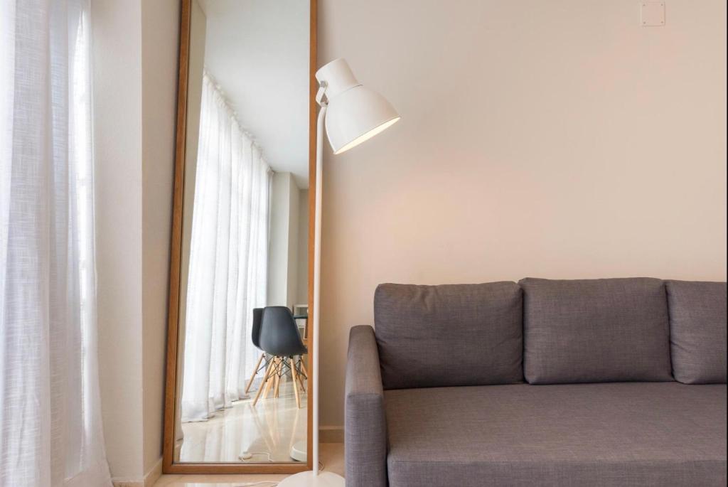 a living room with a couch and a mirror at Gran Apartamento grupo familiar, amigos o trabajo in Málaga