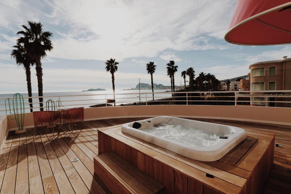 a bath tub on a deck with palm trees and the ocean at Le Rose Thé in La Ciotat