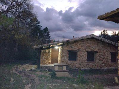 una casa de piedra con un banco delante en Cabaña rural La Dehesa, en Riópar
