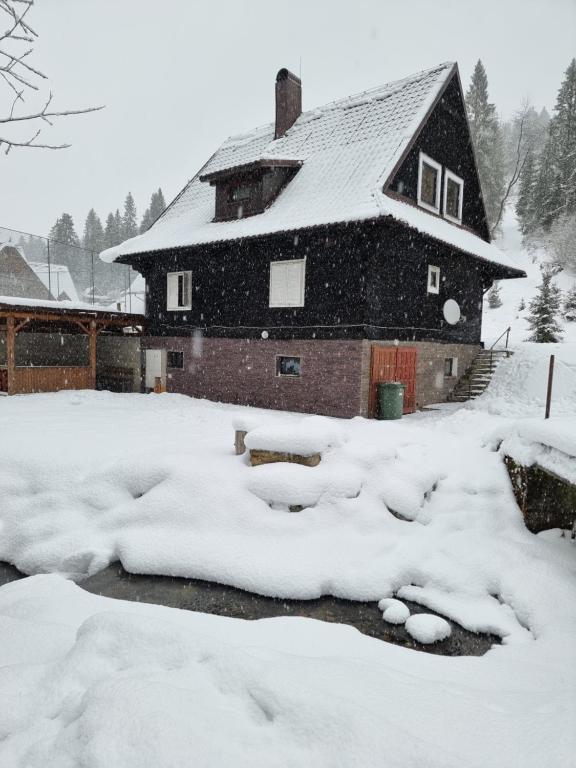 ein schneebedecktes Haus vor der Tür in der Unterkunft Chata Pod Velkou Racou in Oščadnica