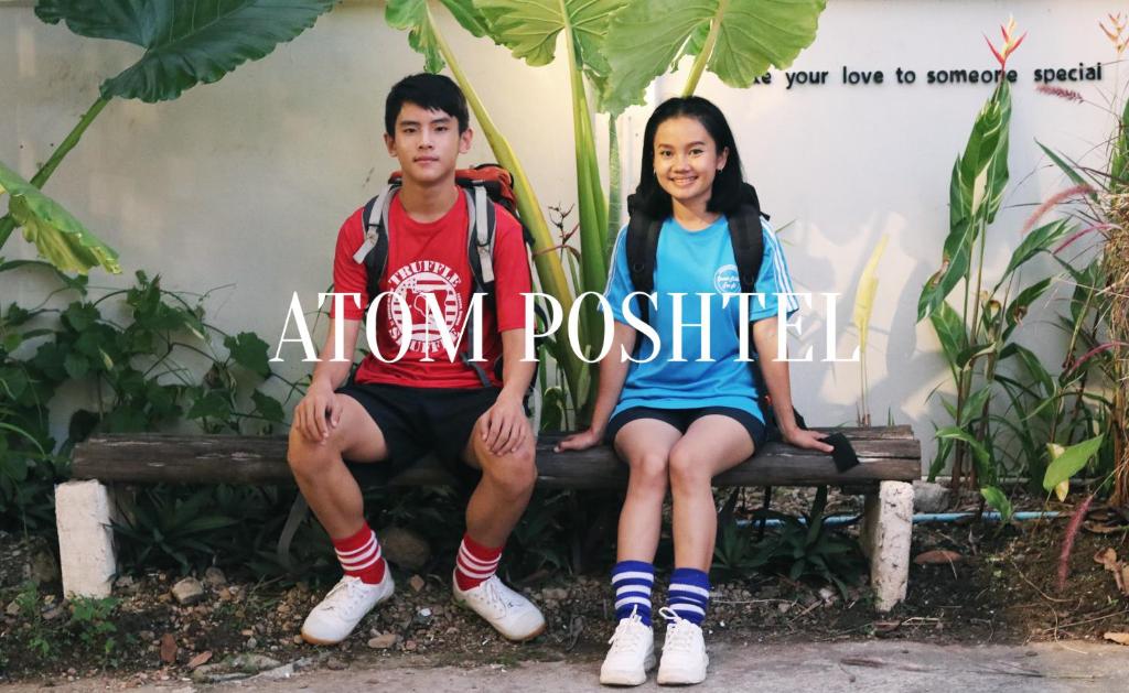Ein Junge und ein Mädchen auf einer Bank in der Unterkunft ATOM Poshtel in Mae Sariang