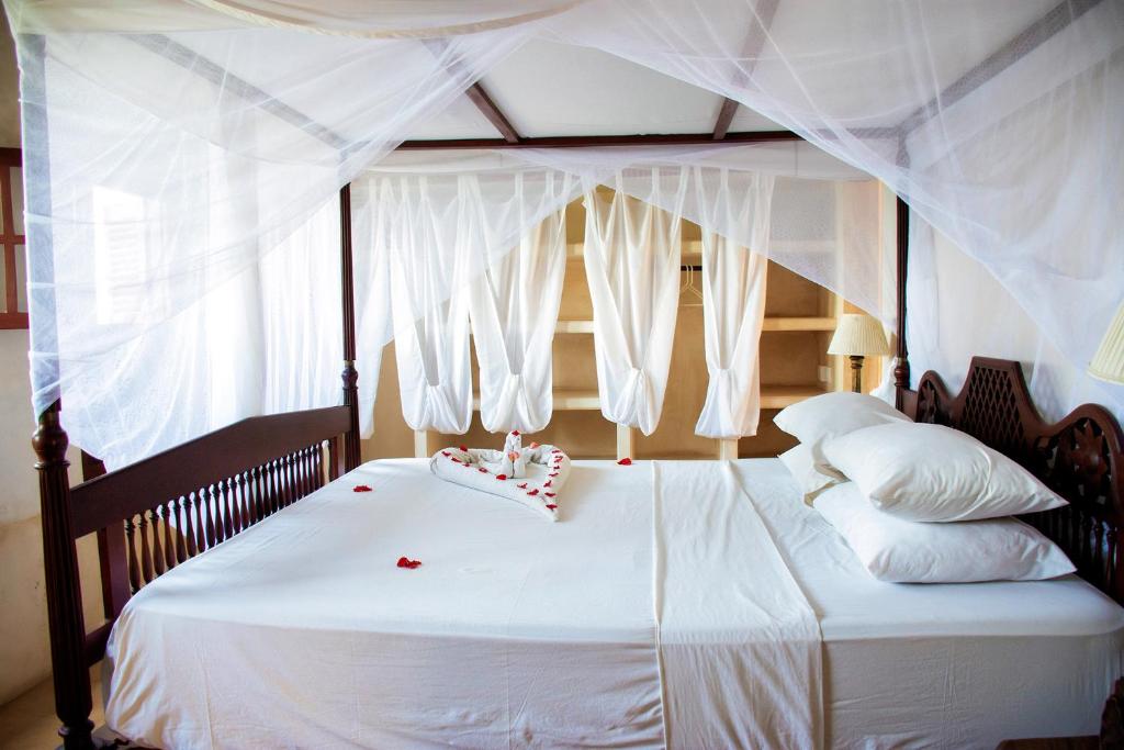 a bedroom with a white bed with a canopy at LAMU HOUSE in Lamu