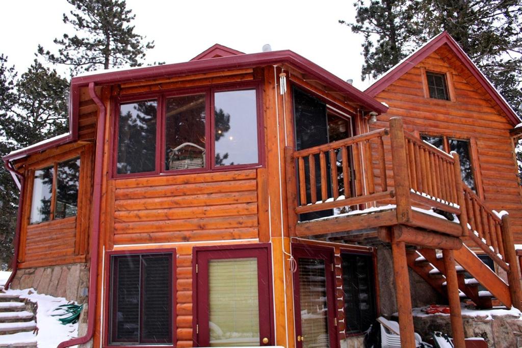eine Hütte im Wald mit einer großen Terrasse in der Unterkunft Mountain Masterpiece by Rocky Mountain Resorts in Allenspark