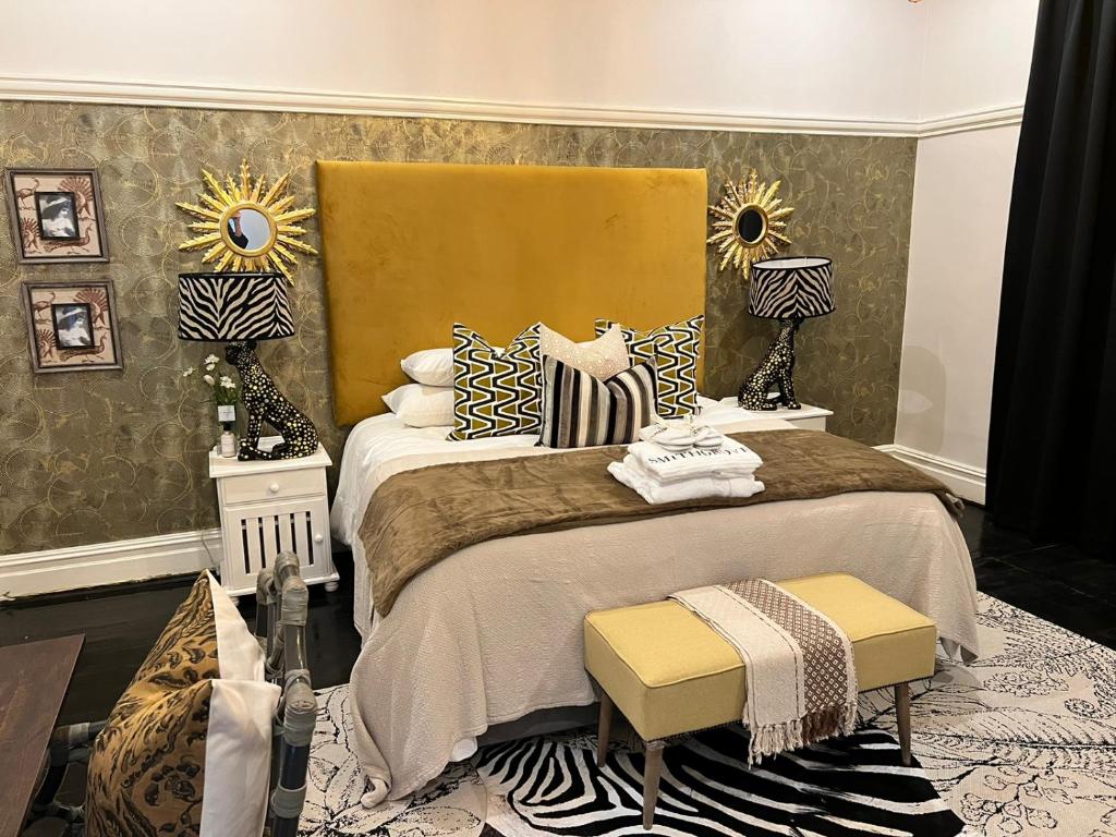 a bedroom with a bed with two lamps and two stools at Smithgrove Guesthouse in Pietermaritzburg