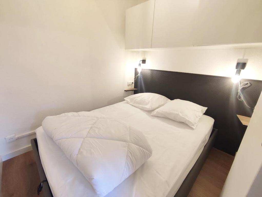 sypialnia z białym łóżkiem i dwiema poduszkami w obiekcie Le cerf charmant, T2, Luchon, wifi, balcon, ascenseur, 4 personnes w mieście Luchon