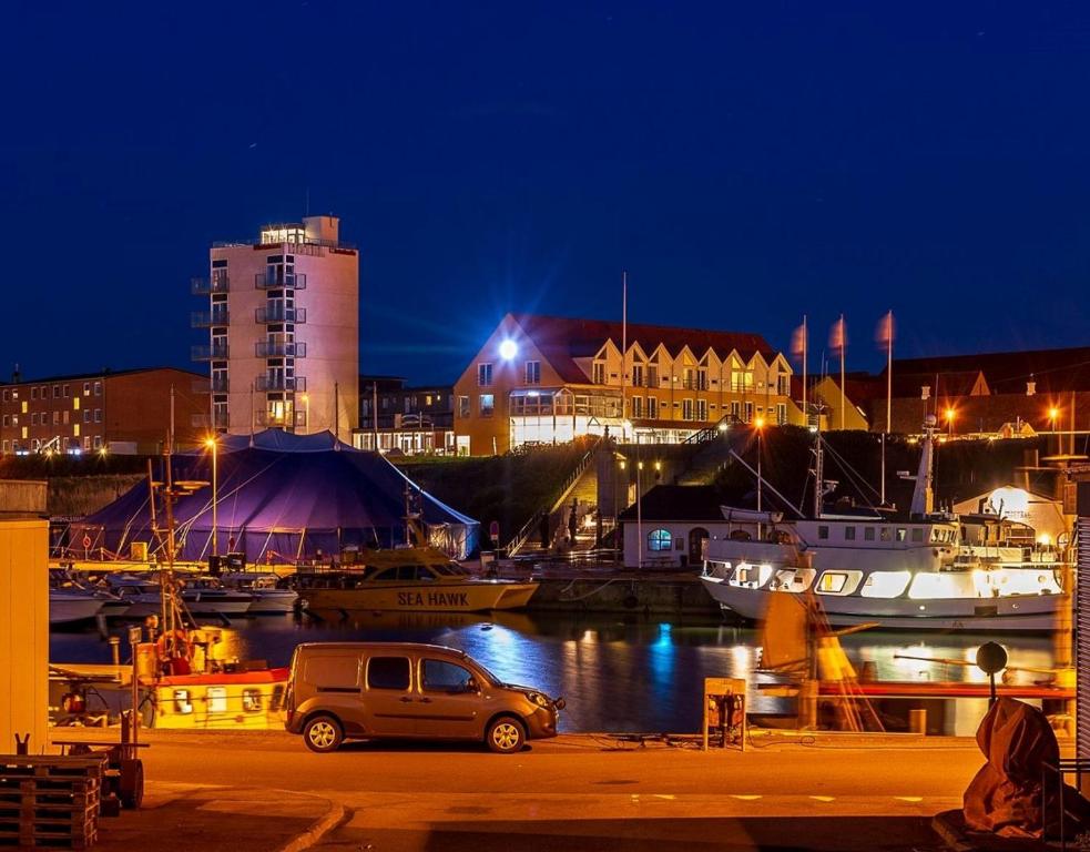 een auto geparkeerd naast een jachthaven 's nachts bij Hotel Hirtshals in Hirtshals