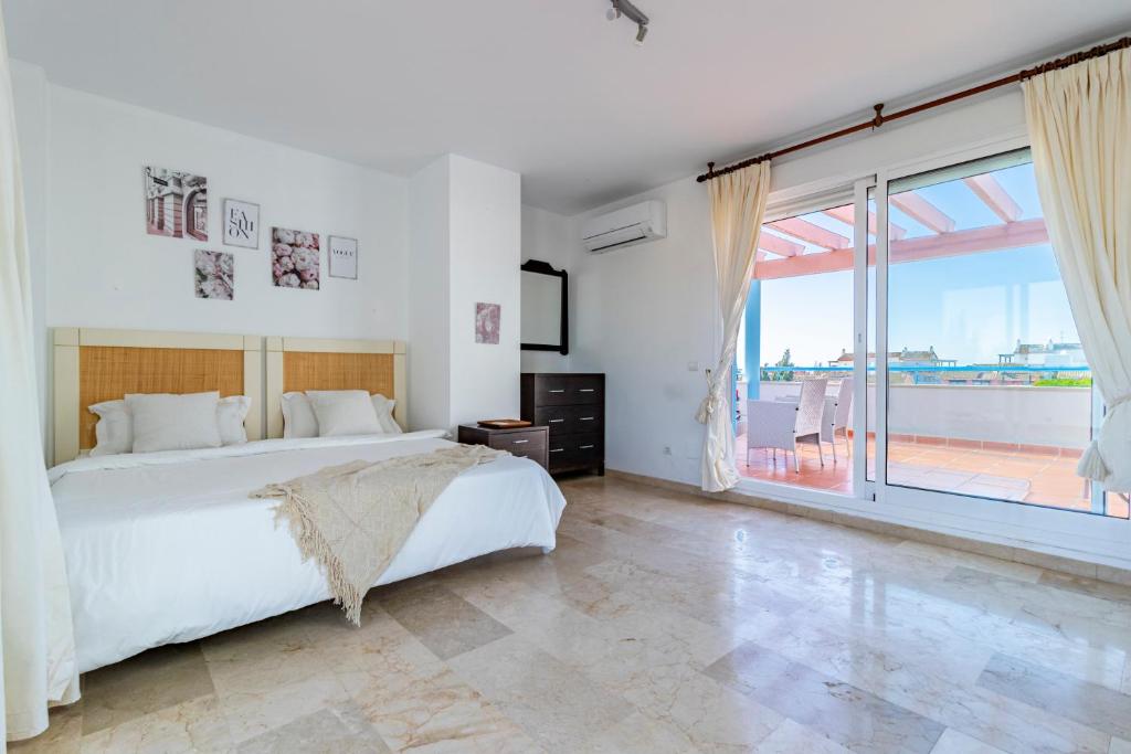 ein weißes Schlafzimmer mit einem Bett und einem großen Fenster in der Unterkunft Casa adosada familiar en complejo con piscina - Bel Air 28 in Estepona