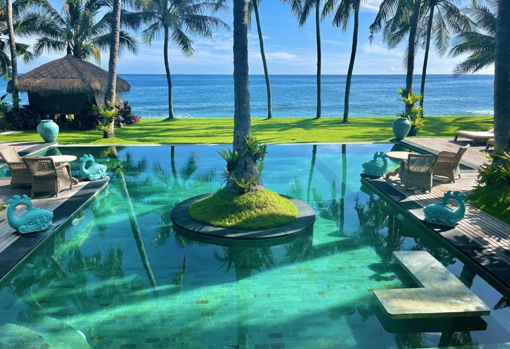 ein Schwimmbad mit dem Ozean im Hintergrund in der Unterkunft Louka Beach Bali in Tianyar