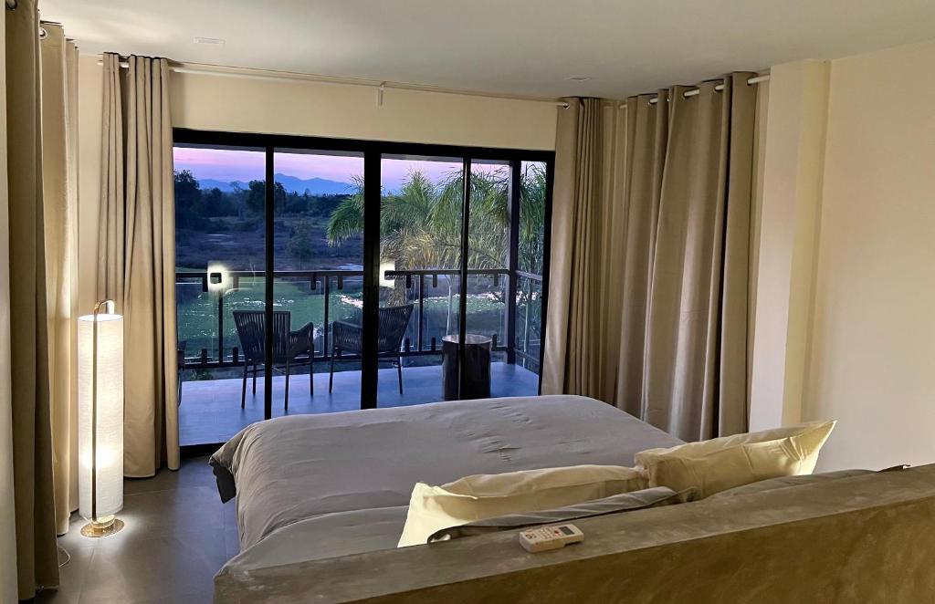 a bedroom with a bed and a large window at I love phants Lodge in Ban Huai Thawai