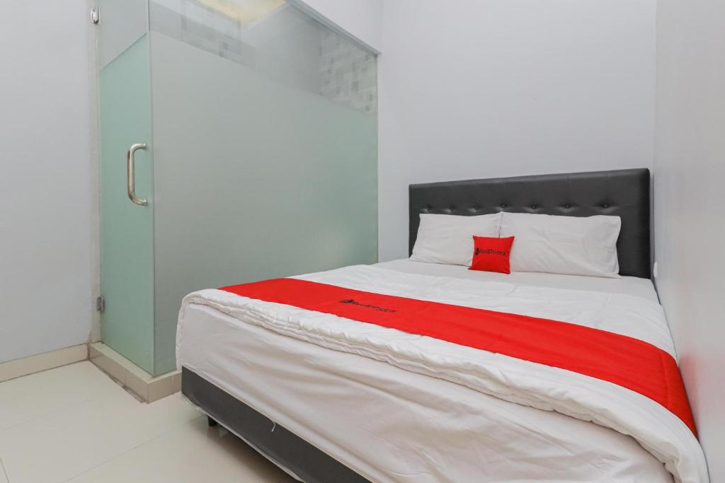 a bedroom with a large bed with a red pillow at RedDoorz at Ngaggel Jaya Surabaya in Surabaya